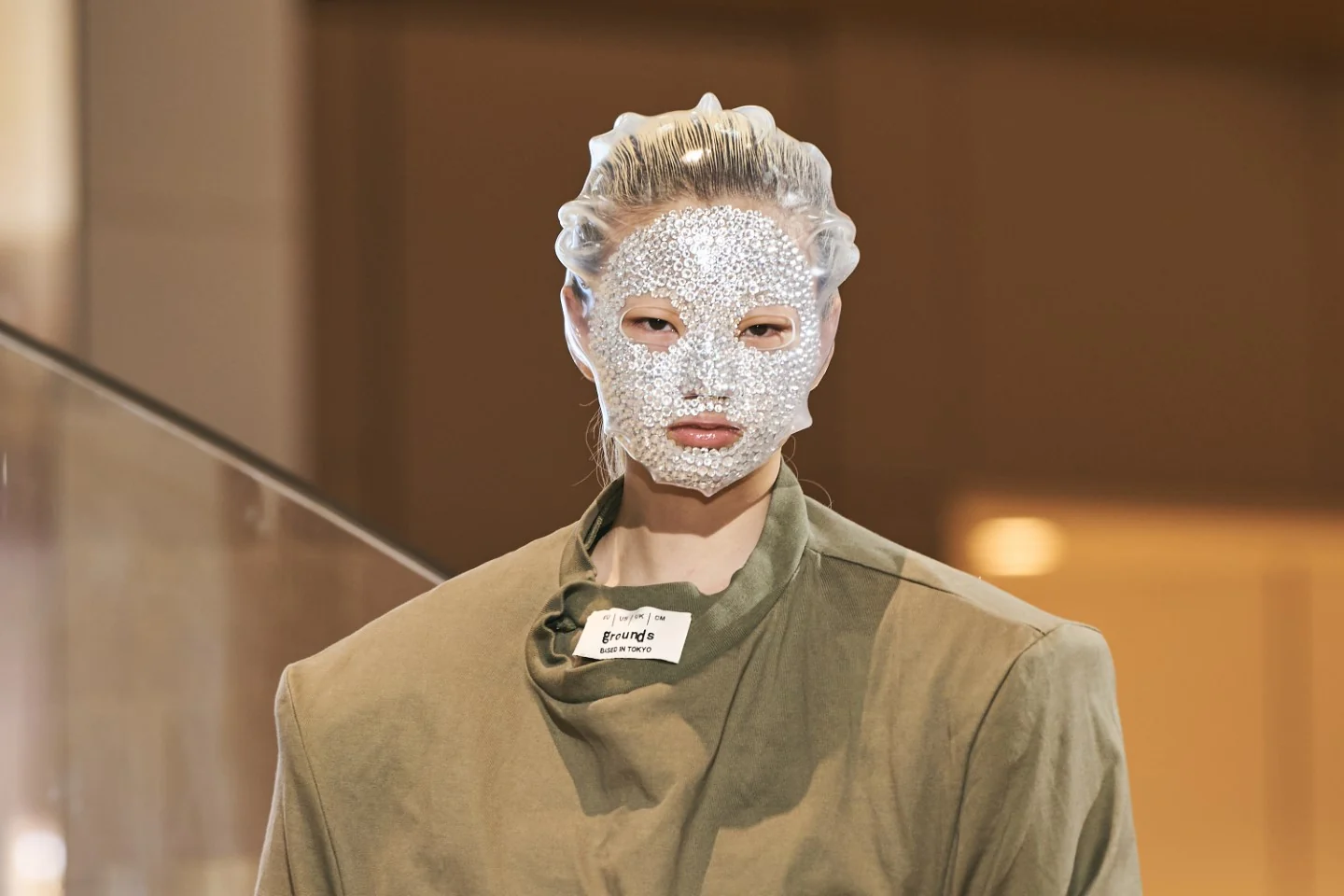 Model wearing a veil and adorned with skin accessories all over her face